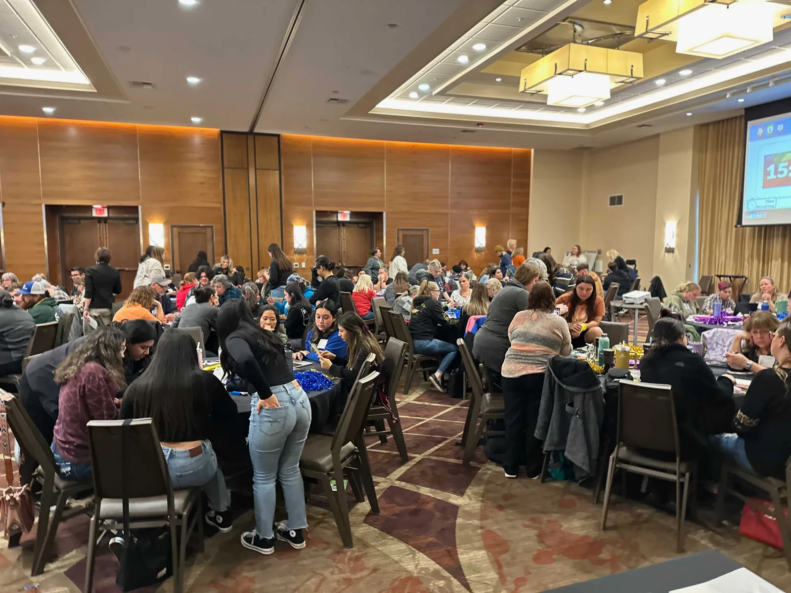 Educators at round tables work through a timed team challenge